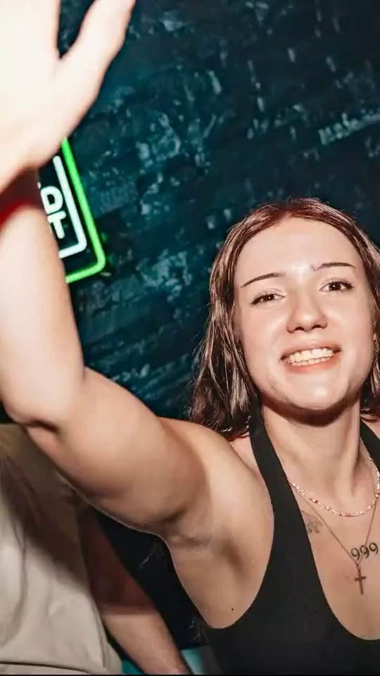 Une fêtarde lève le bras sous les lumières du Club