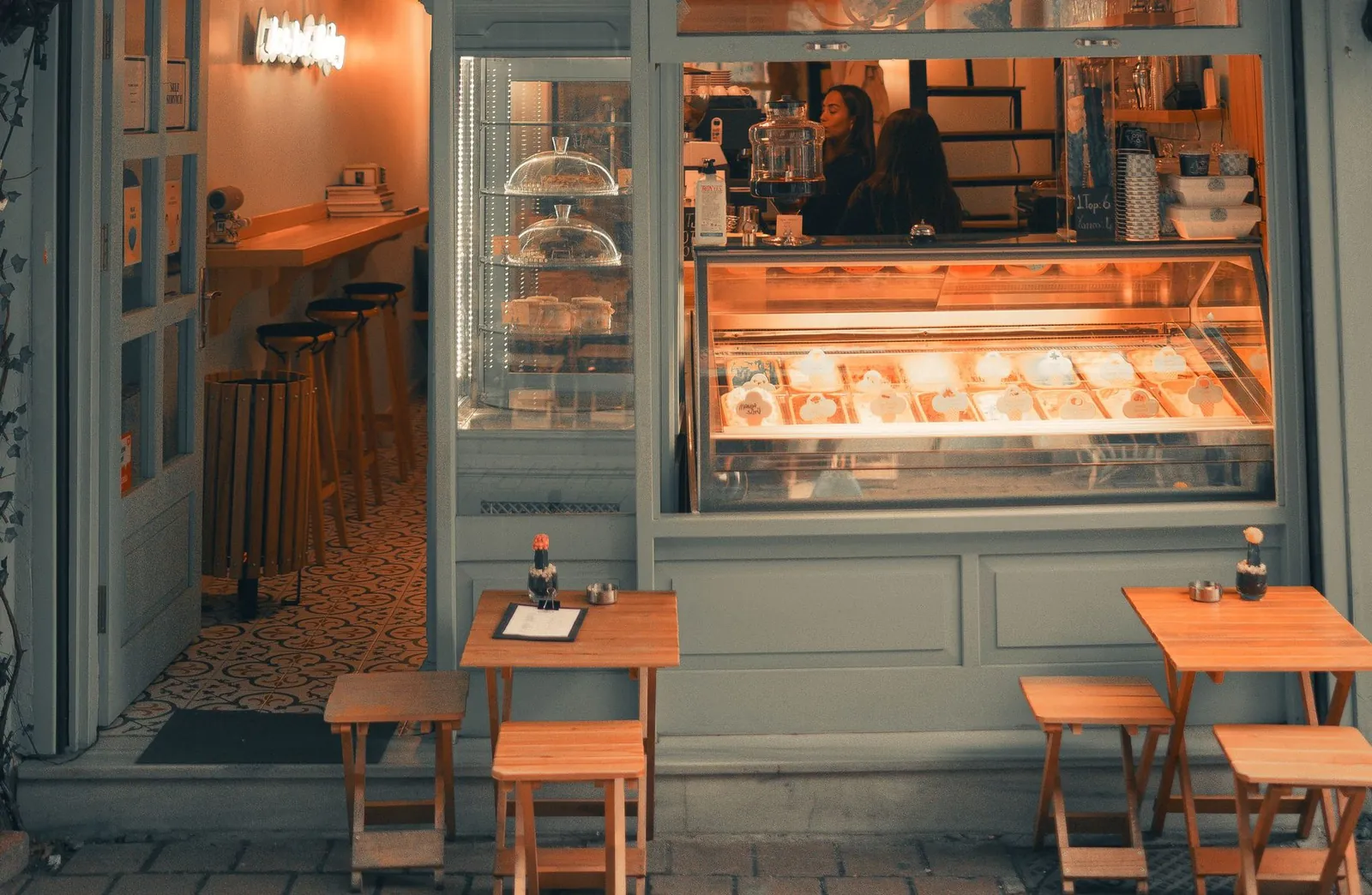 Devanture vert sauge de la boutique, vitrine et petites tables en bois