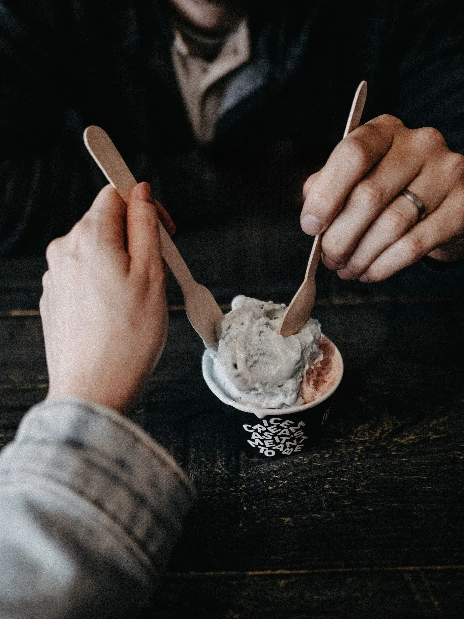 Deux mains partagent un pot de glace en terrasse
